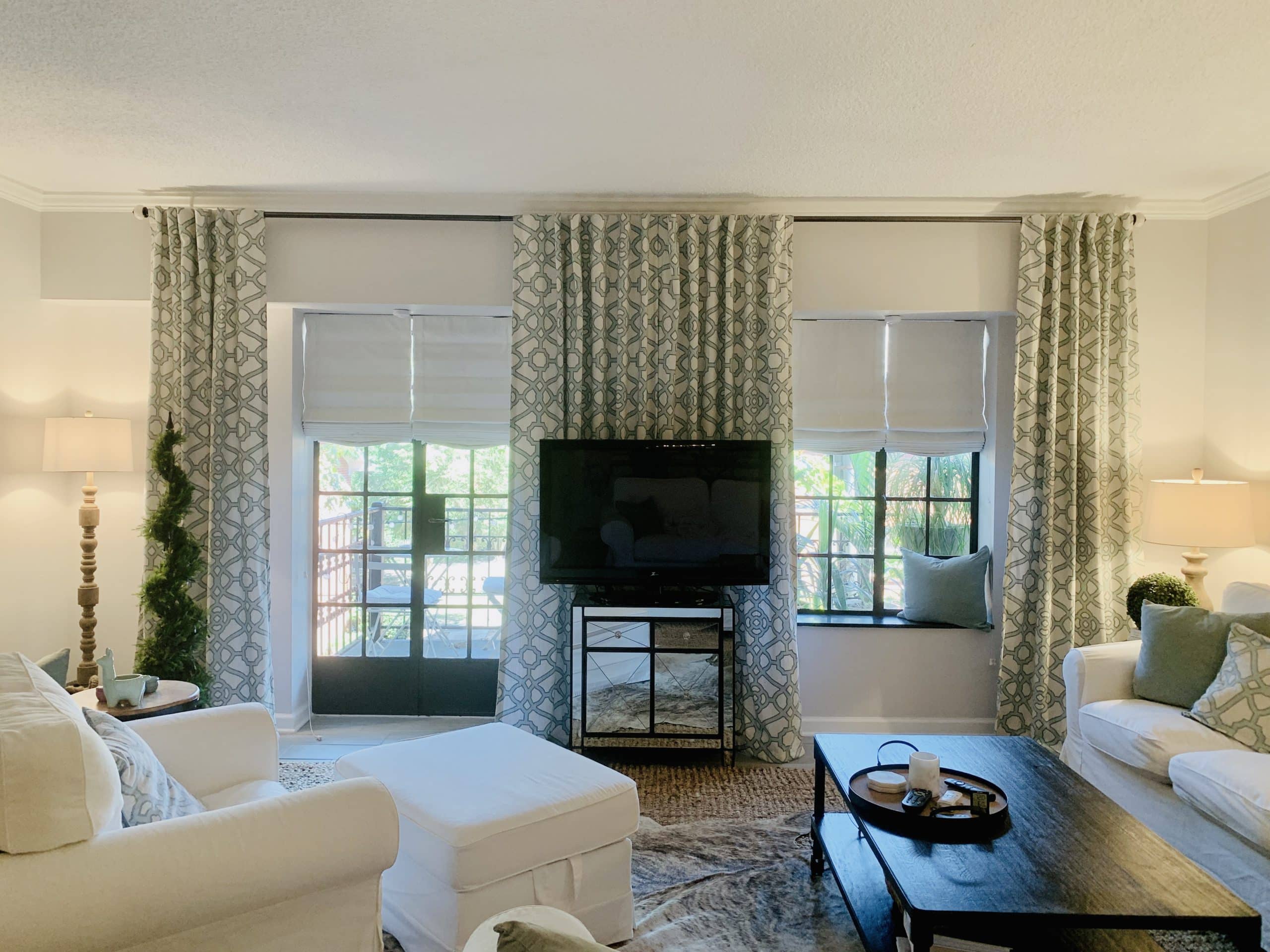 Relaxed White Roman Shades reveal a lush landscape behind this spacious and richly-furnished living room in Atlanta, GA