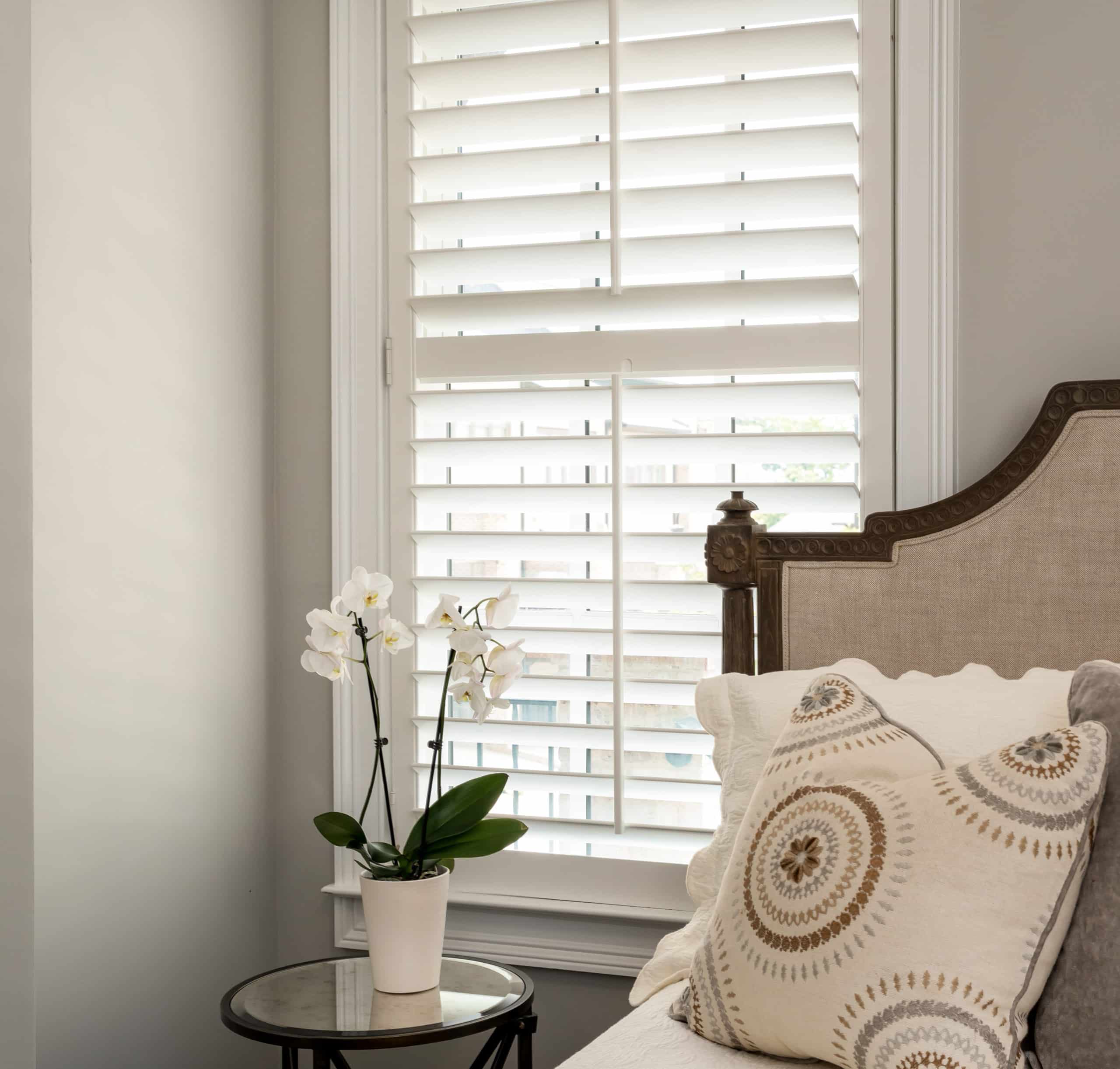 White Hardwood Plantation Shutters with 3.5 inch louvers and a divider rail in a Sandy Springs, GA bedroom