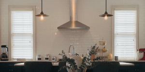White, Corded Faux Wood Blinds featuring 2.5 inch slats filter light in an Alpharetta, GA kitchen with white tiles