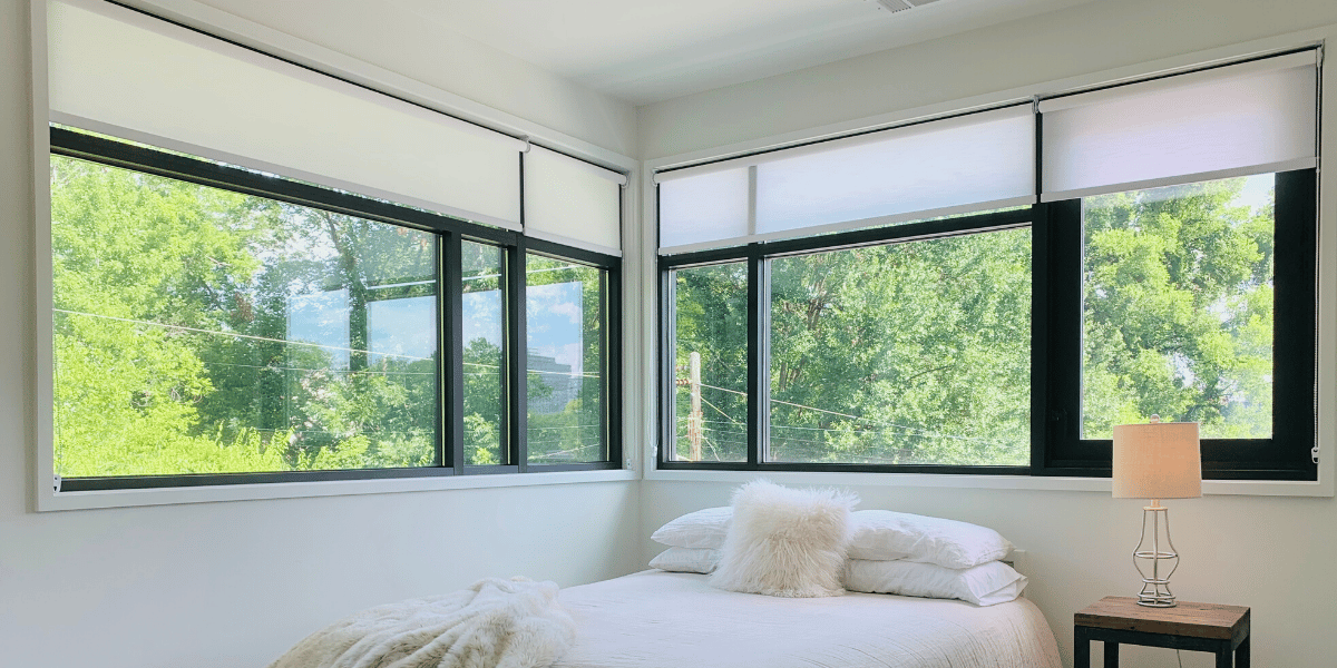 White, Motorized Roller Shades lifted to reveal a green landscape behind a modern white bedroom in Atlanta, GA