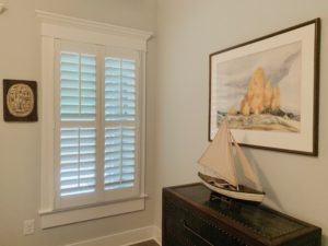 Hardwood Plantation Shutters featuring 3.5 inch louvers and split tilt rods next a model boat in a Decatur, GA guestroom