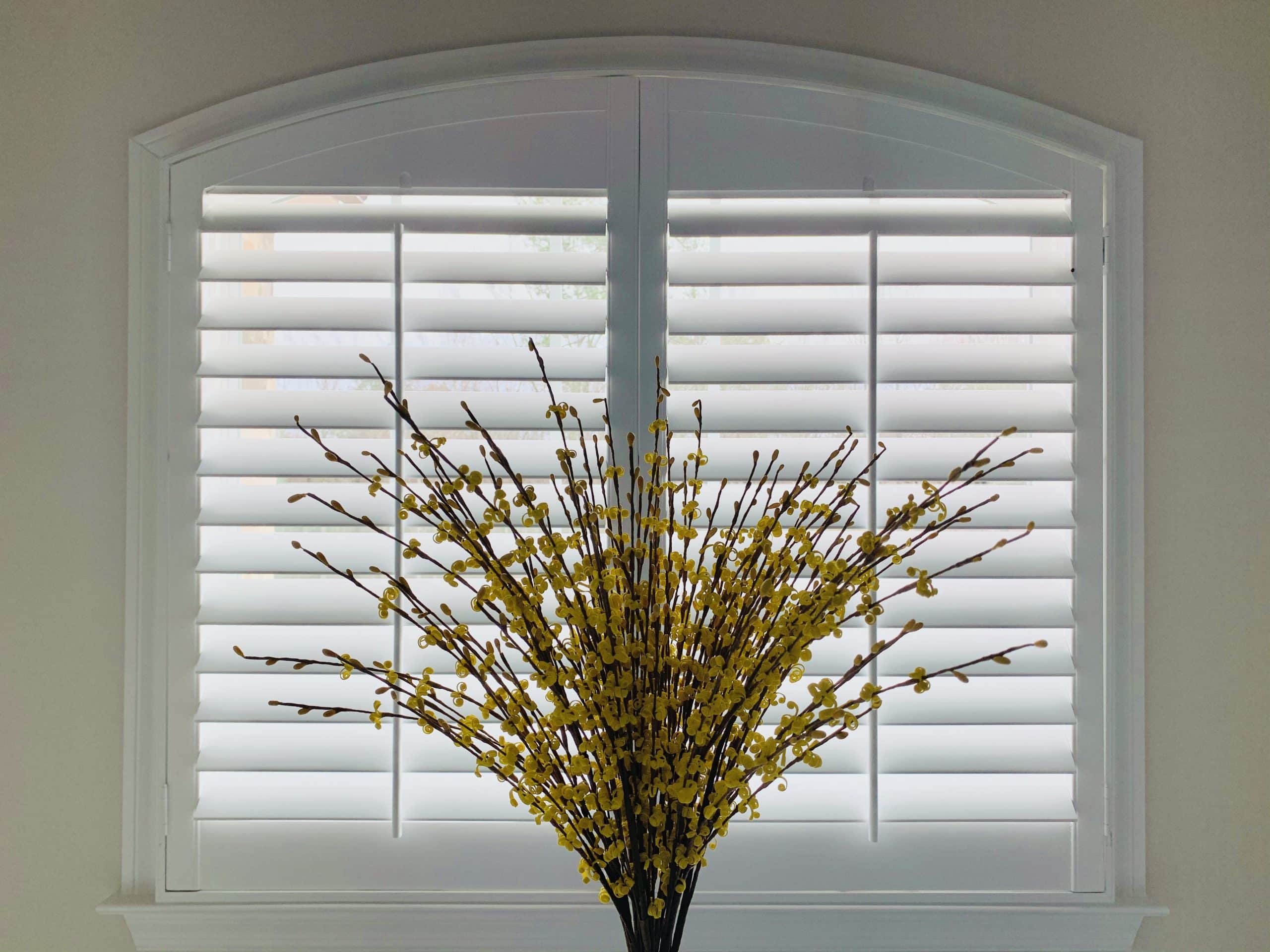 White, Hardwood Plantation Shutters featuring 3.5 inch louvers on a double-paneled, arched window with white trim, in Roswell, GA