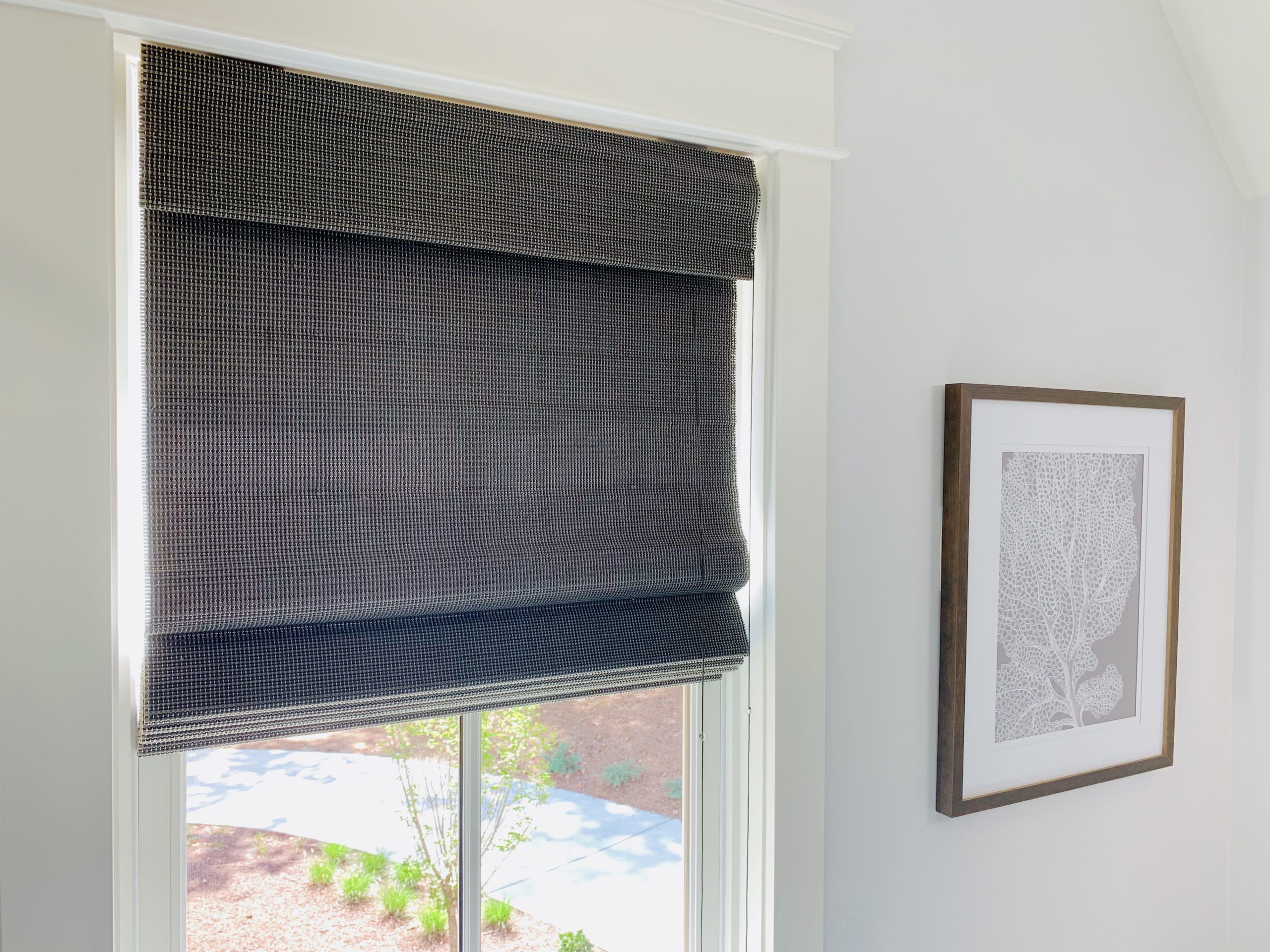 Dark Natural Woven Shades rolled halfway down a window in an Atlanta, GA bathroom