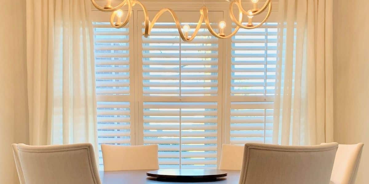 White Plantation Shutters featuring 3.5 inch tapered louvers and divider rails in a warmly lit Nashville, TN dining room