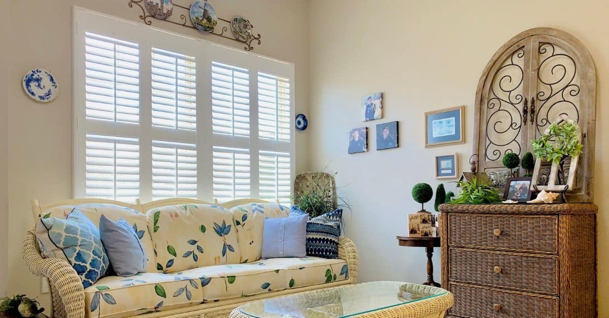 Hardwood Plantation Shutters featuring 2.5 inch louvers and divider rails in a brightly-lit sunroom in Nashville, TN