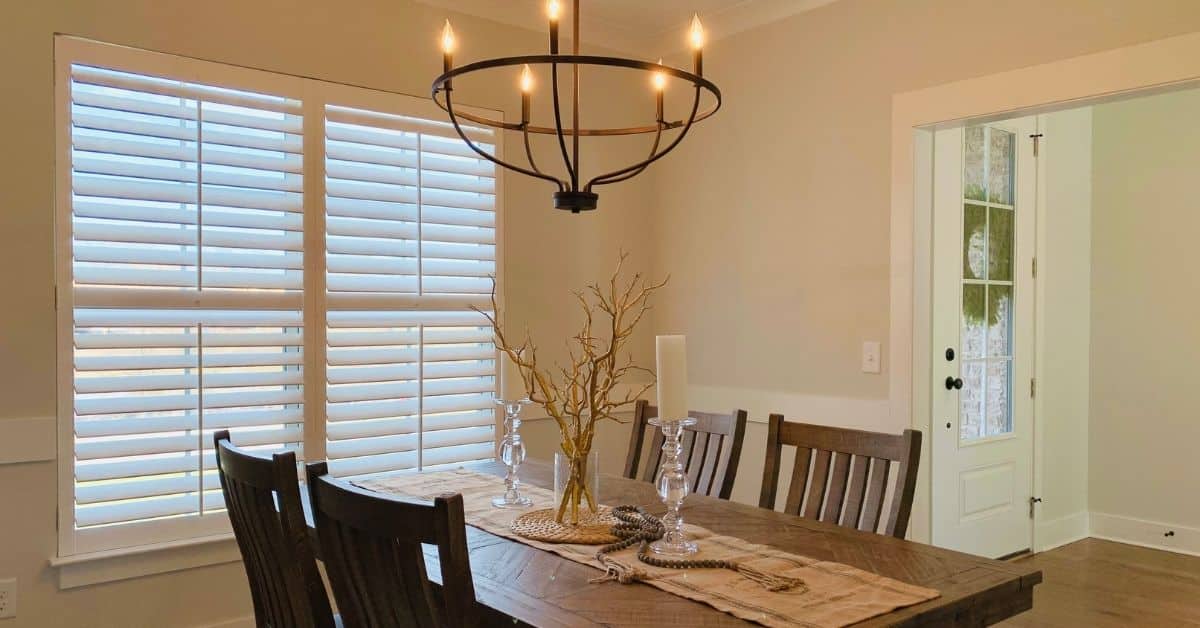 Hardwood Plantation Shutters featuring split tilt rods in a traditional dining room with wooden furniture