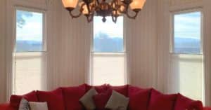 Cellular Shades, also known as Honeycomb Shades, featuring top down, buttom up lift functionality, above a red couch in a historic Woodbury, TN estate