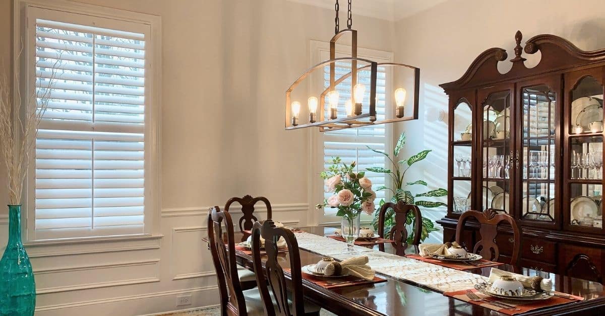 Hardwood Plantation Shutters featuring 3.5 inch louvers and split tilt rods in a traditional, white-trimmed dining room