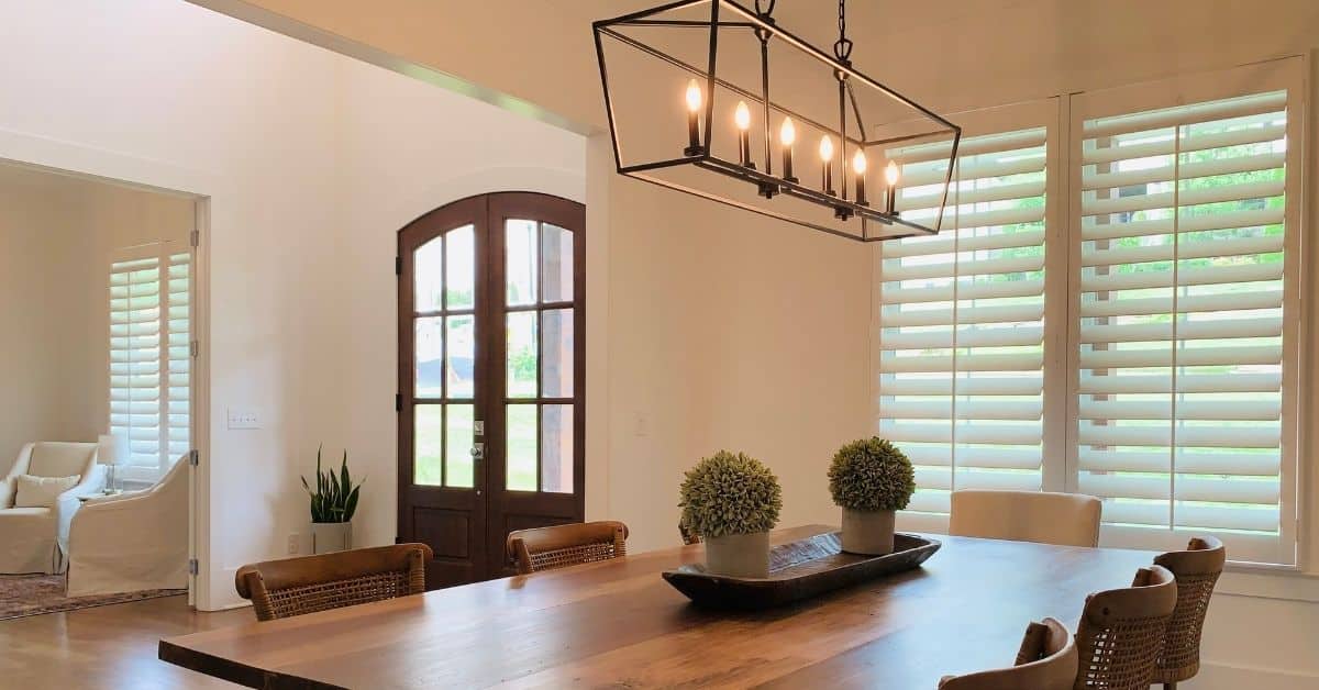 White, Hardwood Plantation Shutters with 4.5 inch louvers in a spacious dining room and living room foyer