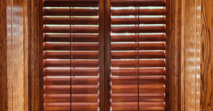 Cherry-stained Hardwood Plantation Shutters featuring 4.5 inch louvers in a rich, wooden library in Brentwood TN.