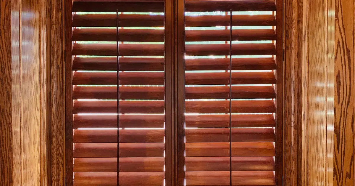 Cherry-stained Hardwood Plantation Shutters featuring 4.5 inch louvers in a rich, wooden library in Brentwood TN.