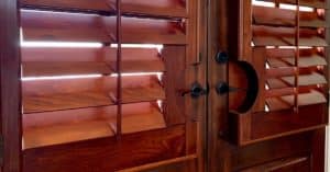 Dark-Stained Hardwood Plantation Shutters featuring 4.5 inch louvers with door handle cutouts on a rich french door in Brentwood, TN