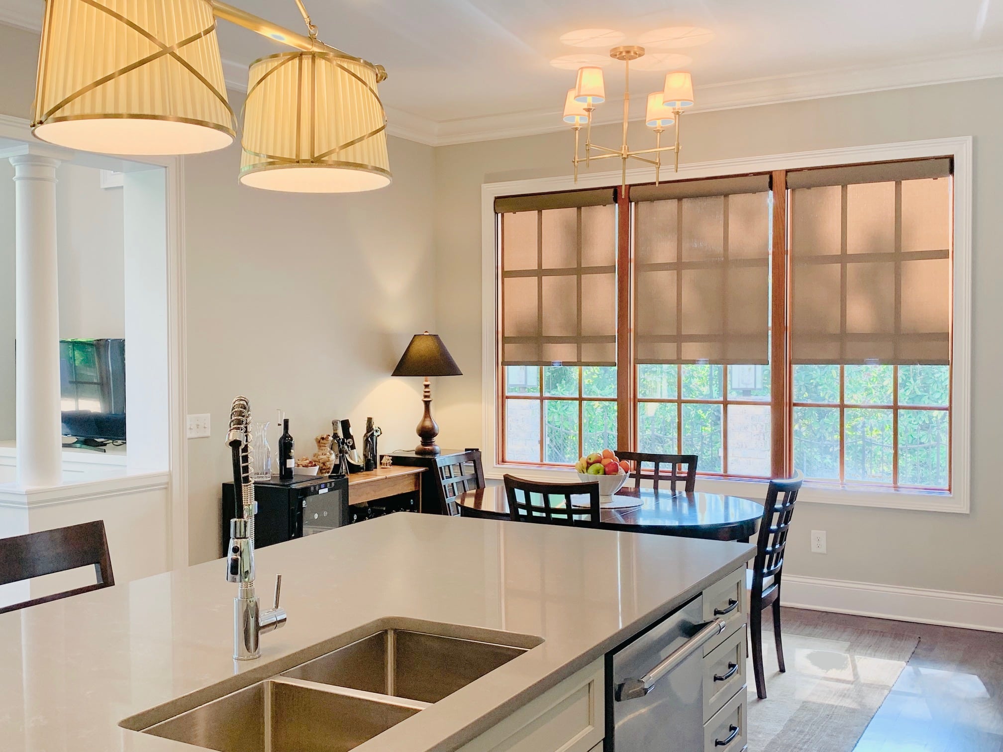 Two Brown roller shades lowered halfway down on three large windows in an open kitchen and dining room area