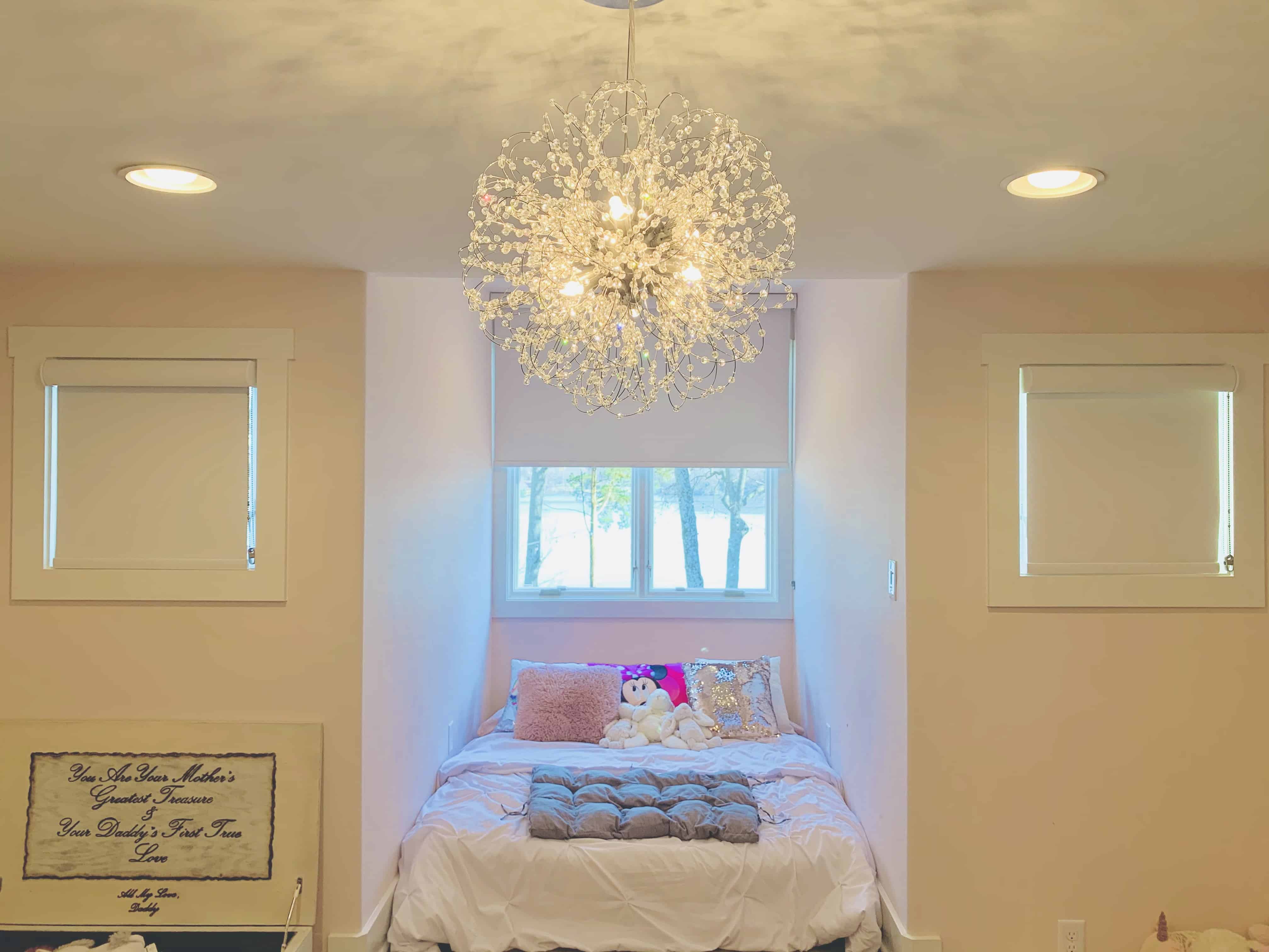 Two white roller shades cover two small windows on either side of a bed in a child's bedroom