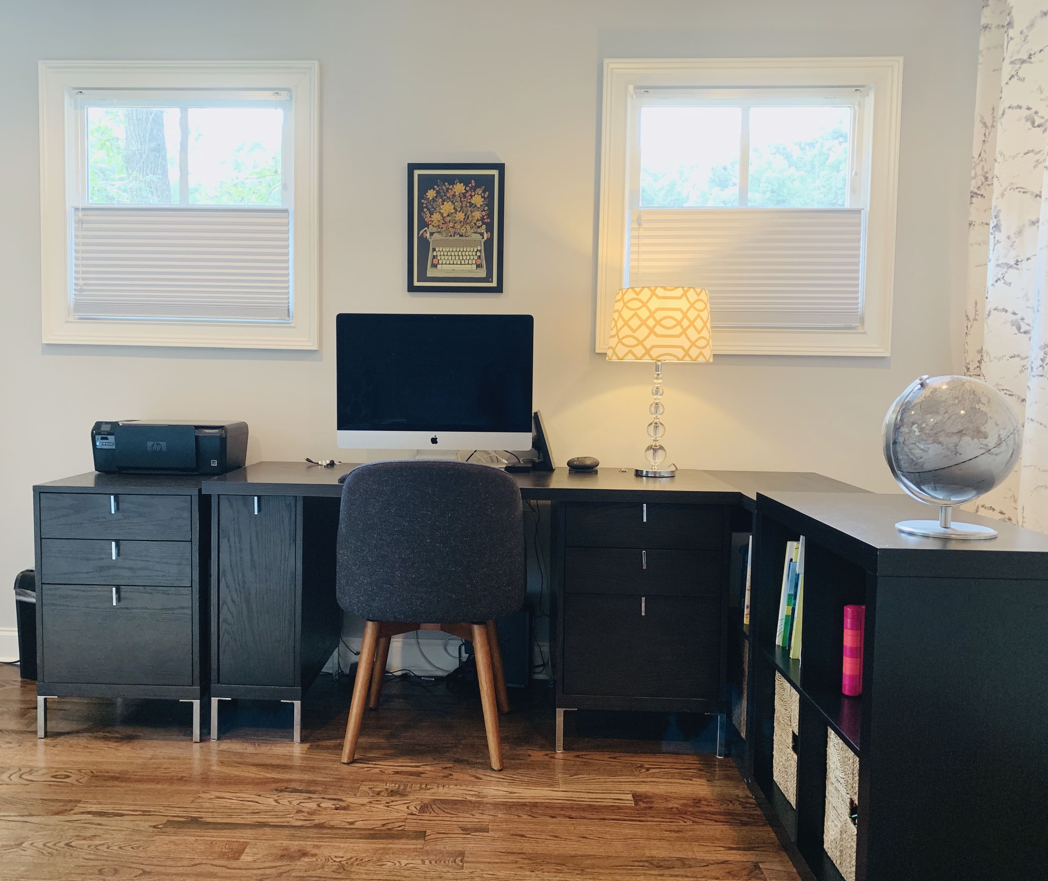 Two top down bottom up cellular shades partially cover two windows above a desk in a home office