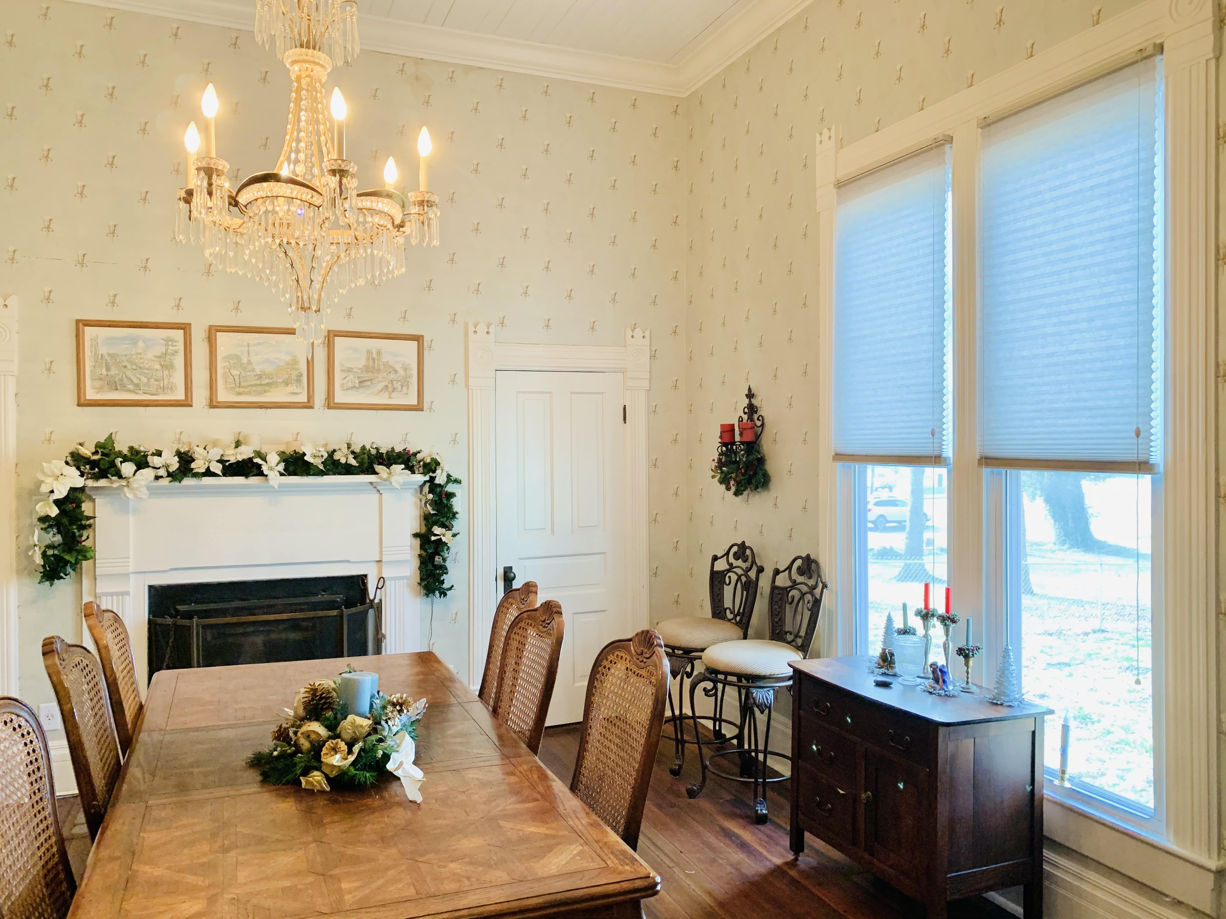 Cellular shades cover two large windows beside a dining room table