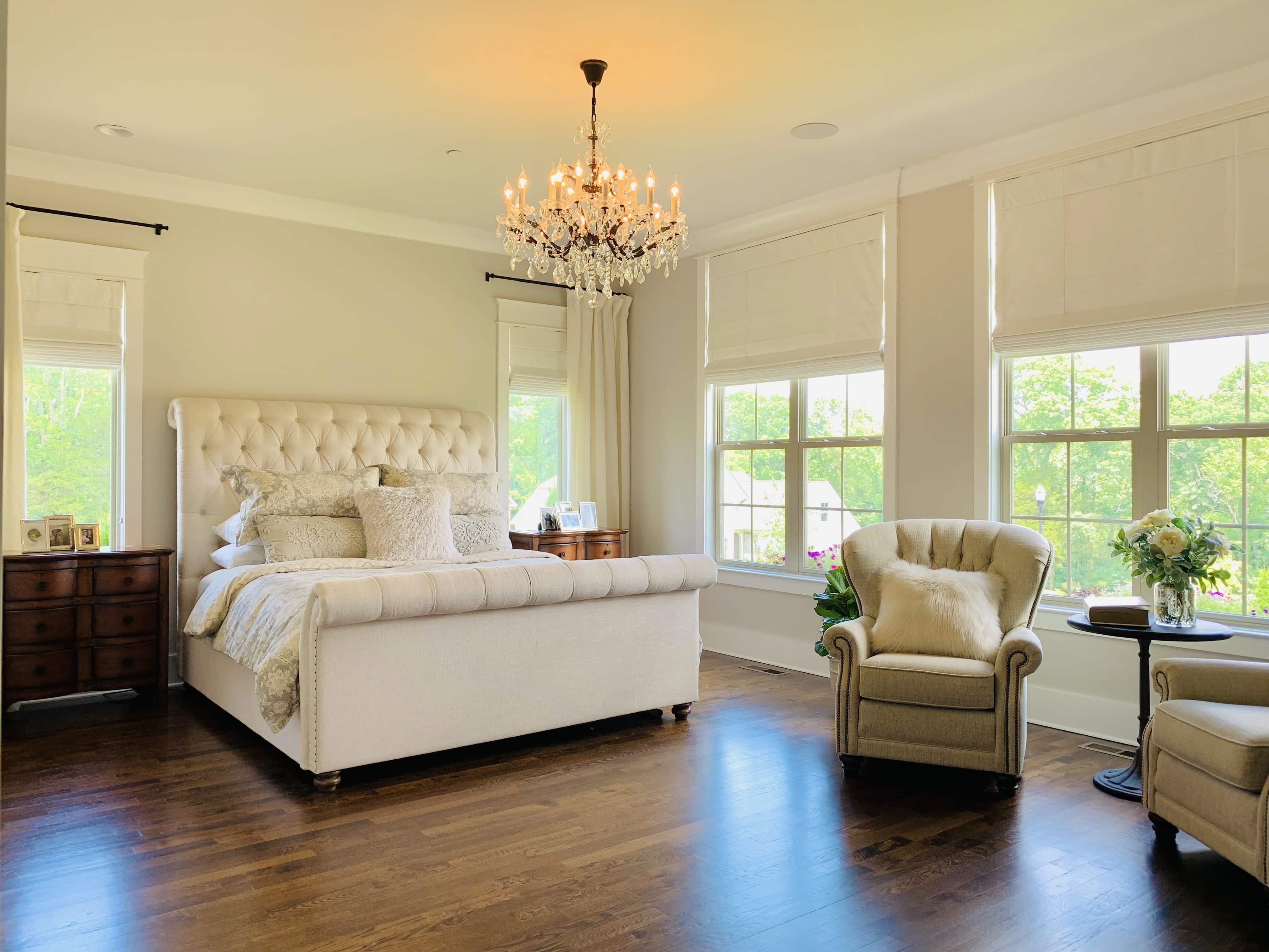 Four roman shades rolled down halfway covering four large windows in a bedroom