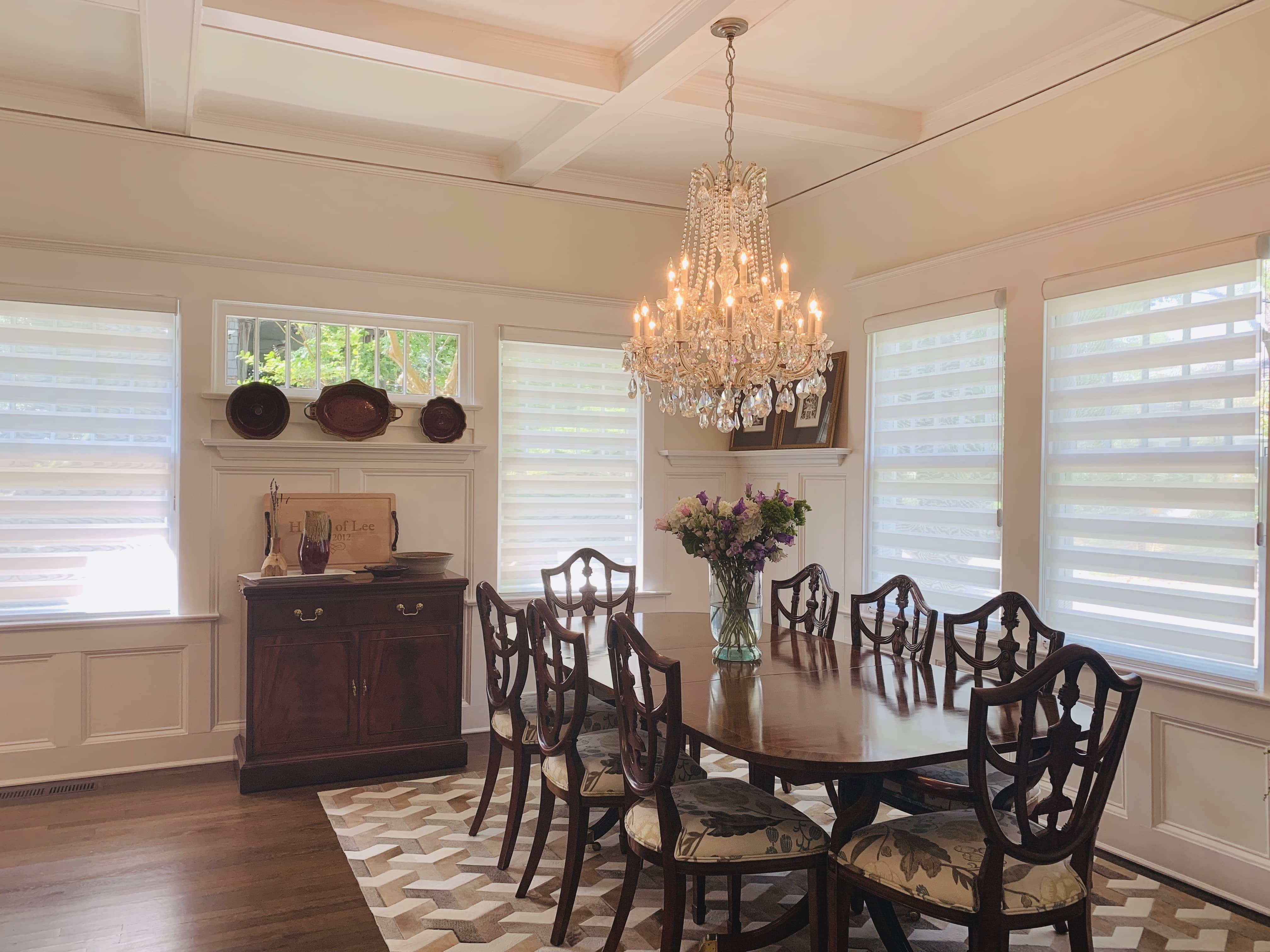 Layered shades in their open position on four windows in a large dining room