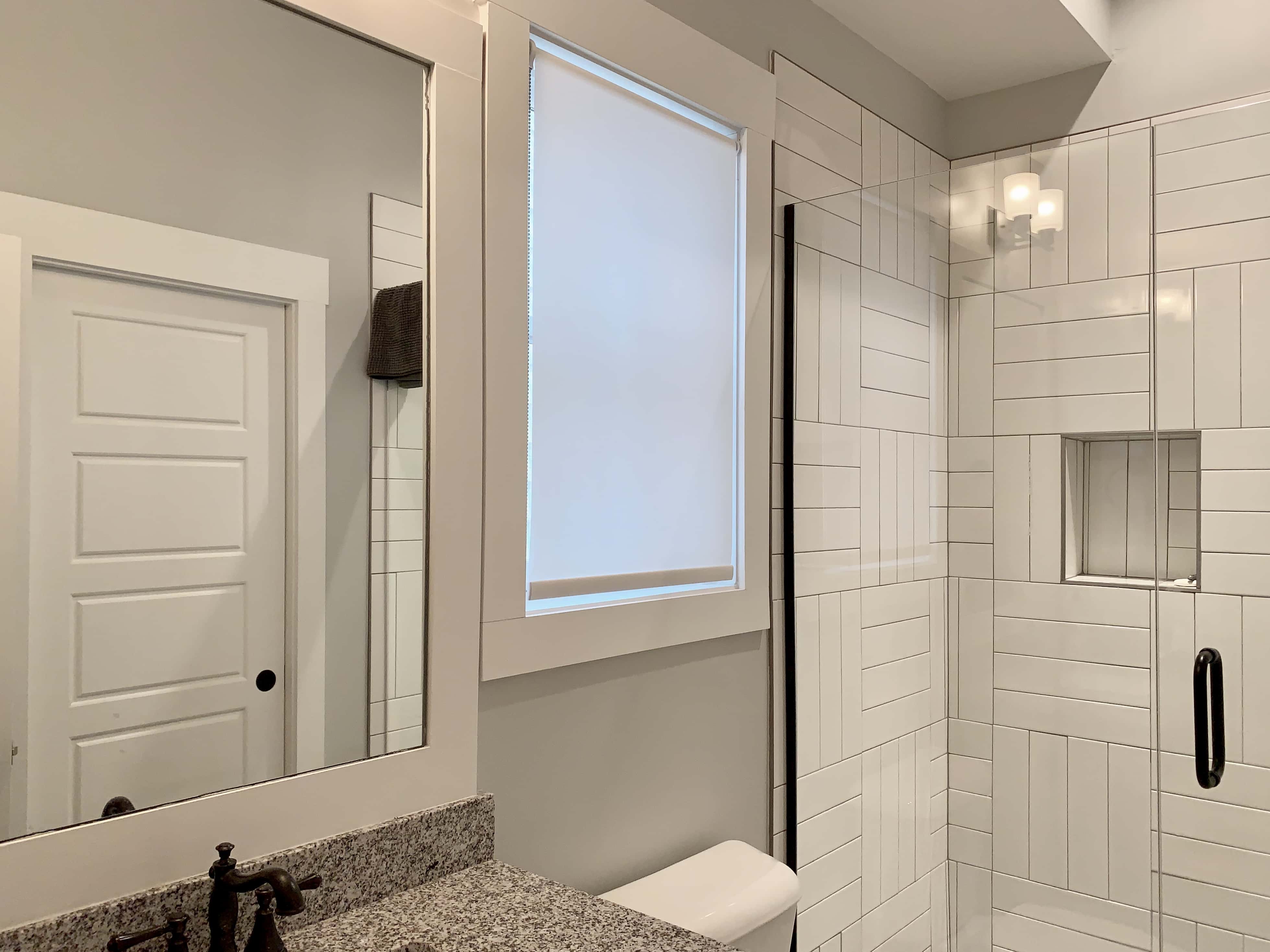 A white roller shade diffuses light into a bathroom