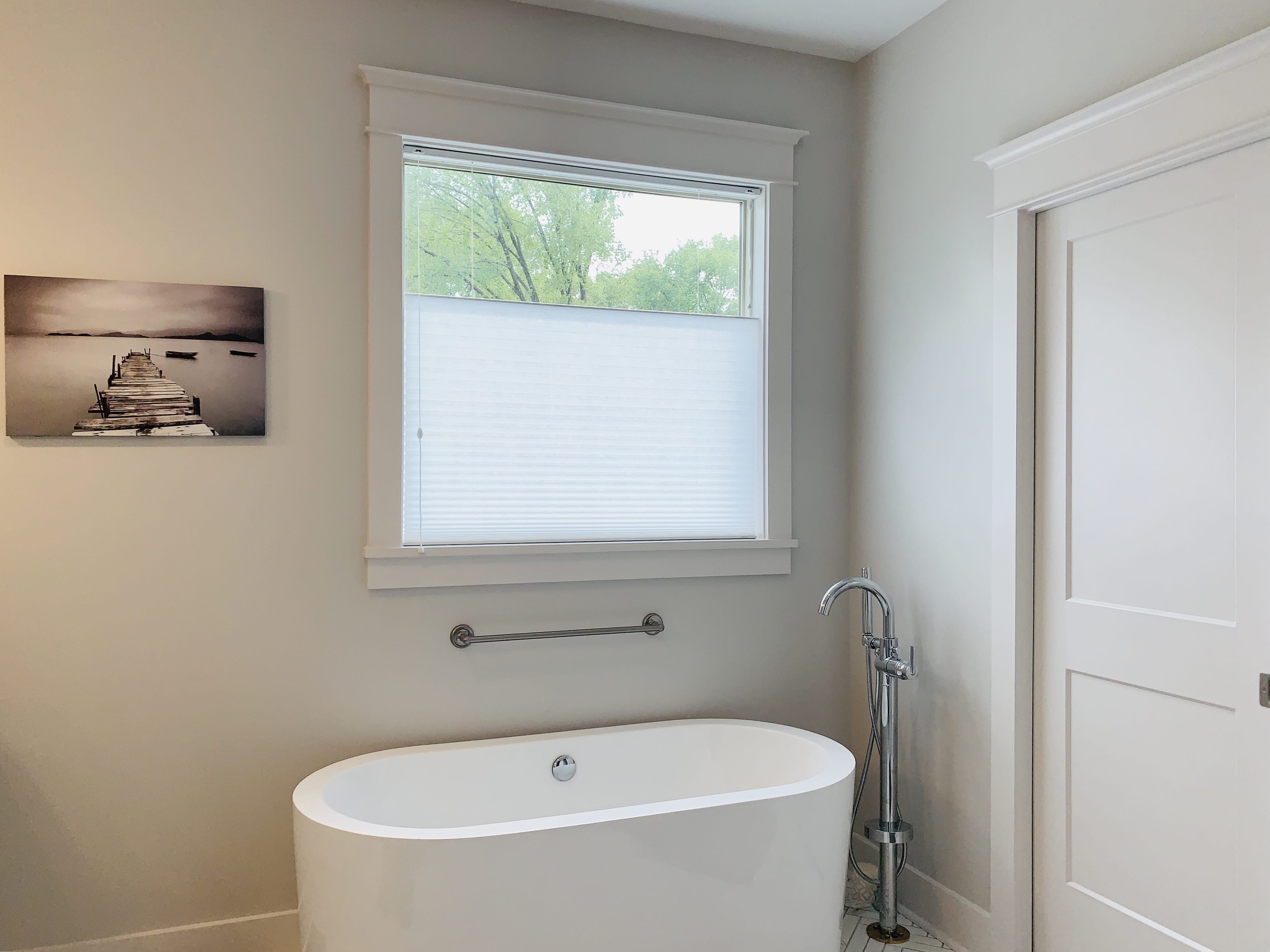 Top down bottom up cellular shades cover a window above a white bathtub